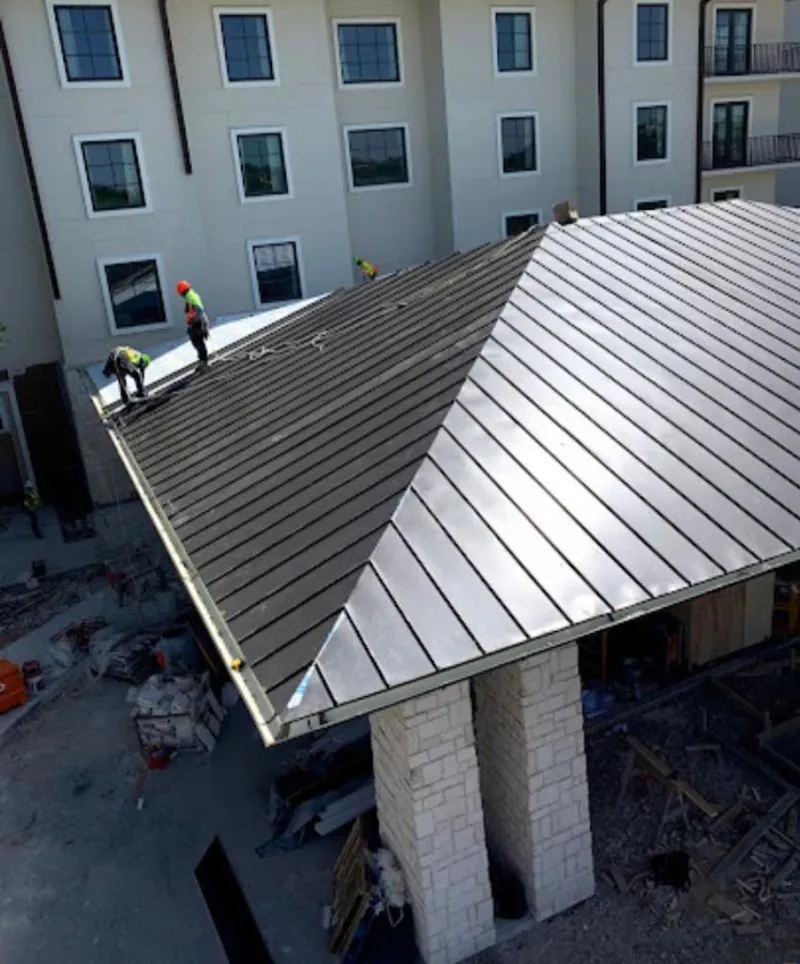 Crew installing standing seam metal roof panels on a commercial project in Grenada